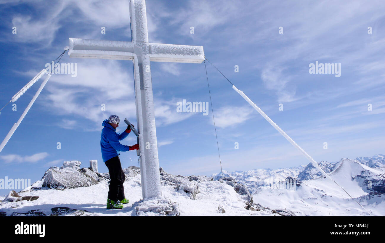 Backcountry maschio sciatore al vertice di croce di un elevato picco alpino su una bella giornata invernale Foto Stock