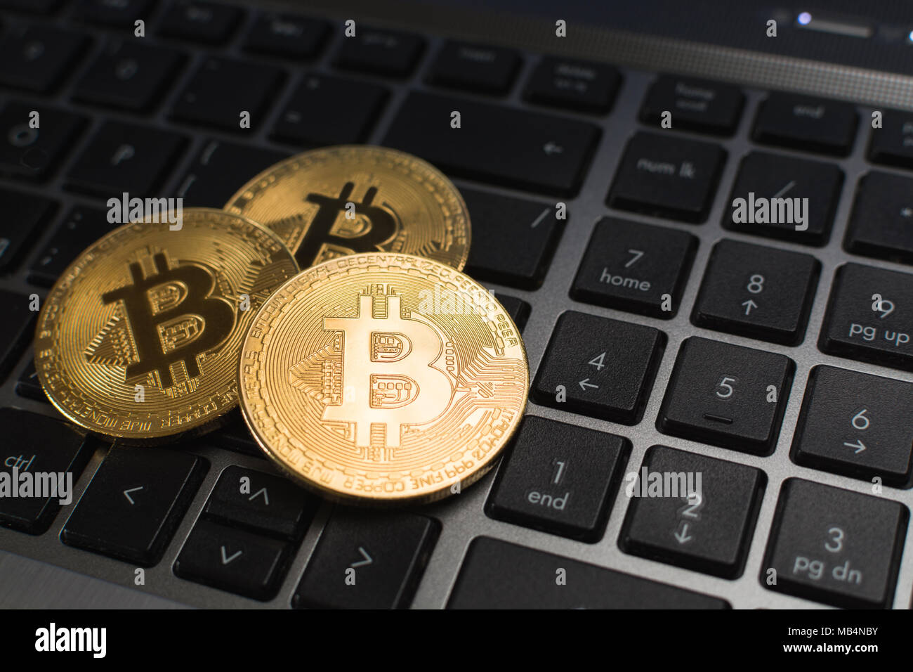 Bitcoin cryptocurrency monete giacente sulla tastiera del notebook, sfondo sfocato Foto Stock