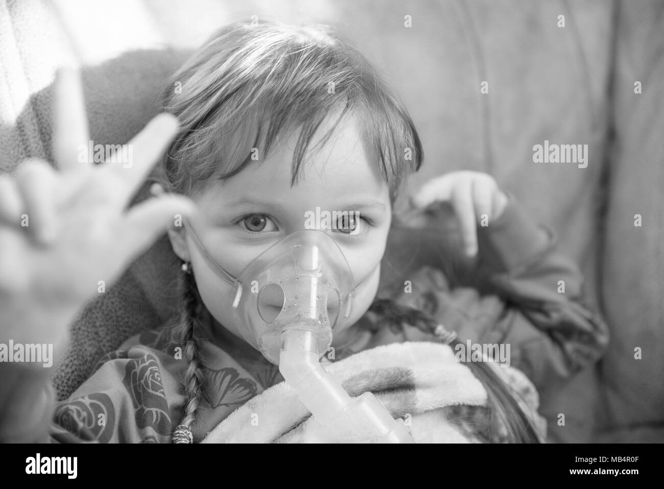 Bambina in una maschera, trattamenti del tratto respiratorio con un nebulizzatore a casa Foto Stock