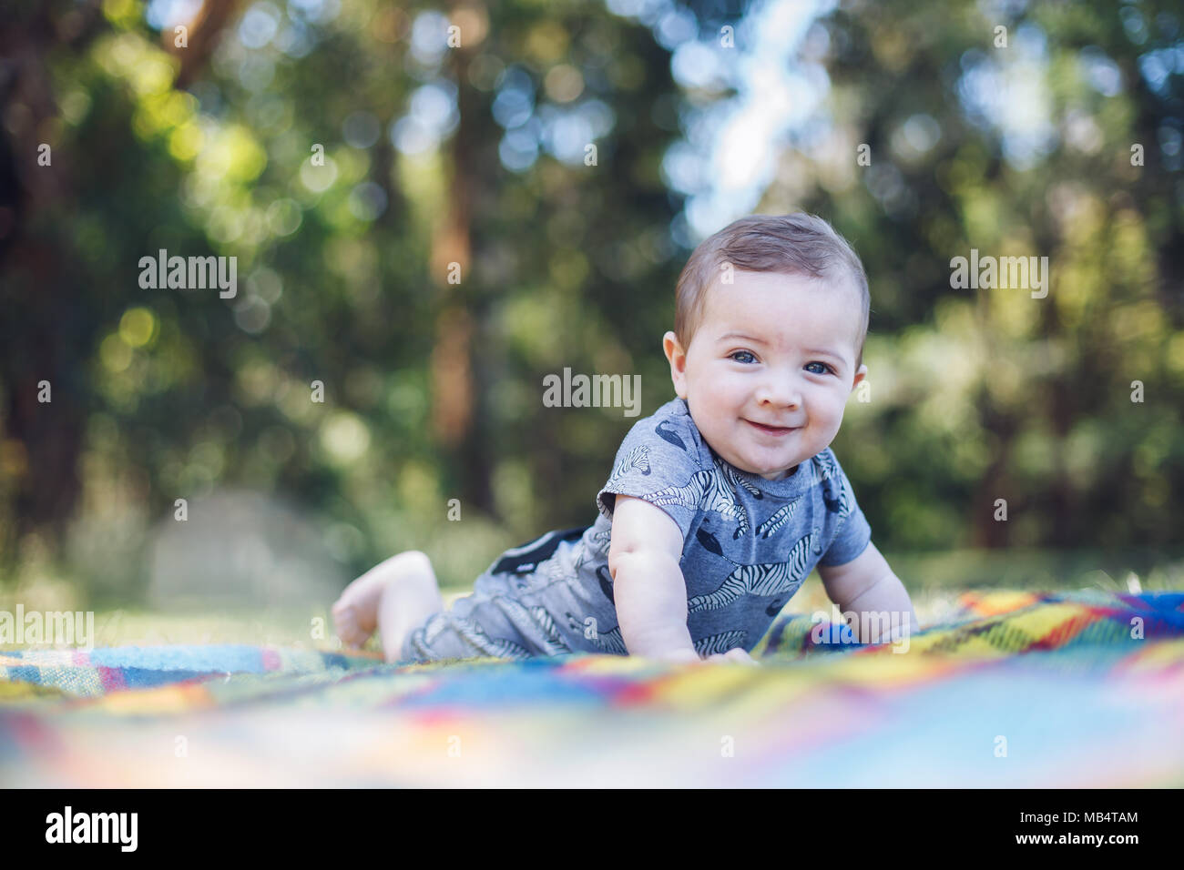 Felice bambino di 6 mesi boy a pancia in giù su un picnic rug Foto Stock