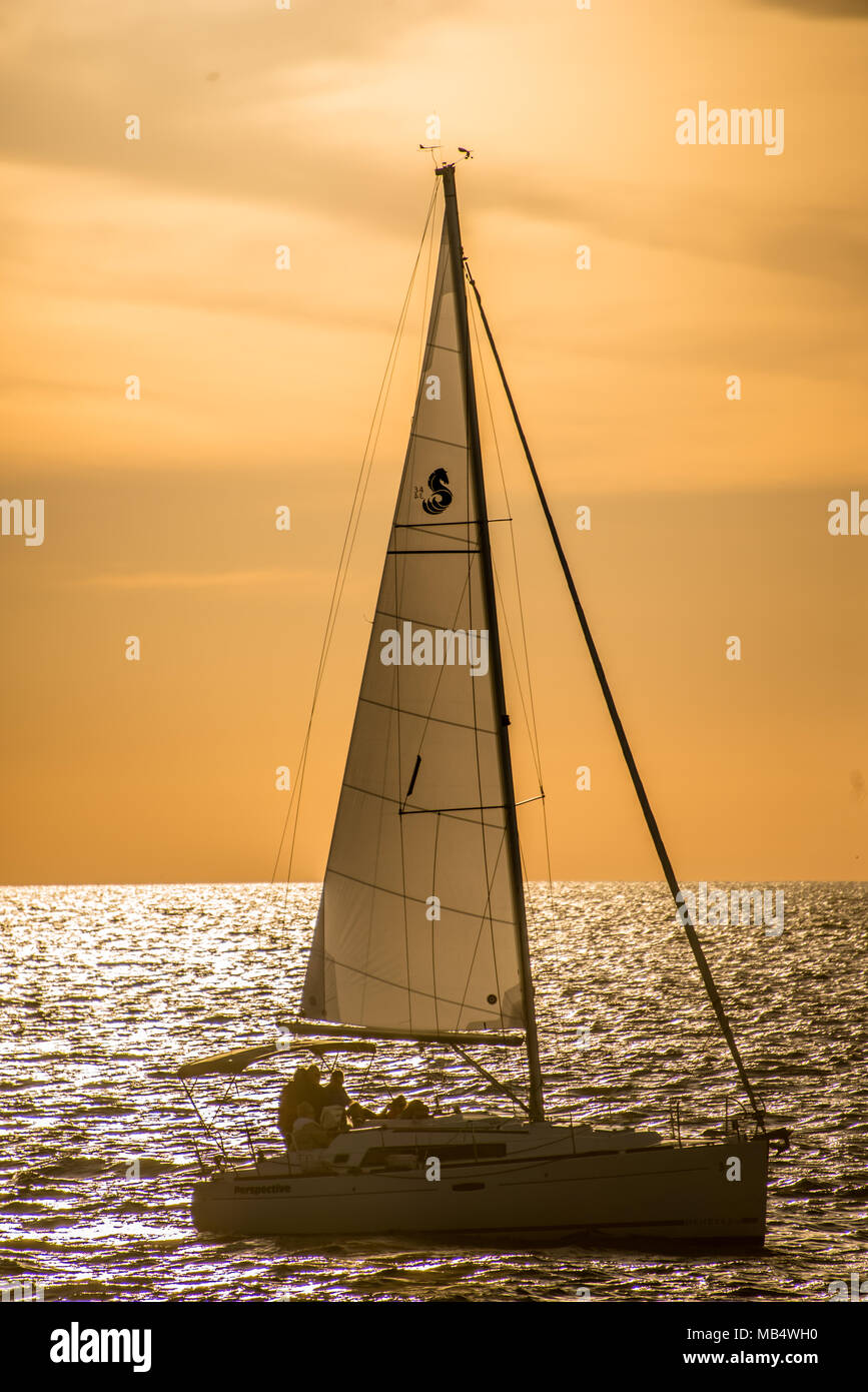 Barca a vela vela in oceano contro amber sky sulla giornata di sole Foto Stock