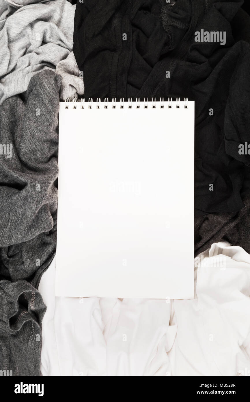 Confezionamento di abiti monocromatici in bianco e nero la valigia. Lista di imballaggio in bianco per notebook. Vista superiore, spazio di copia Foto Stock