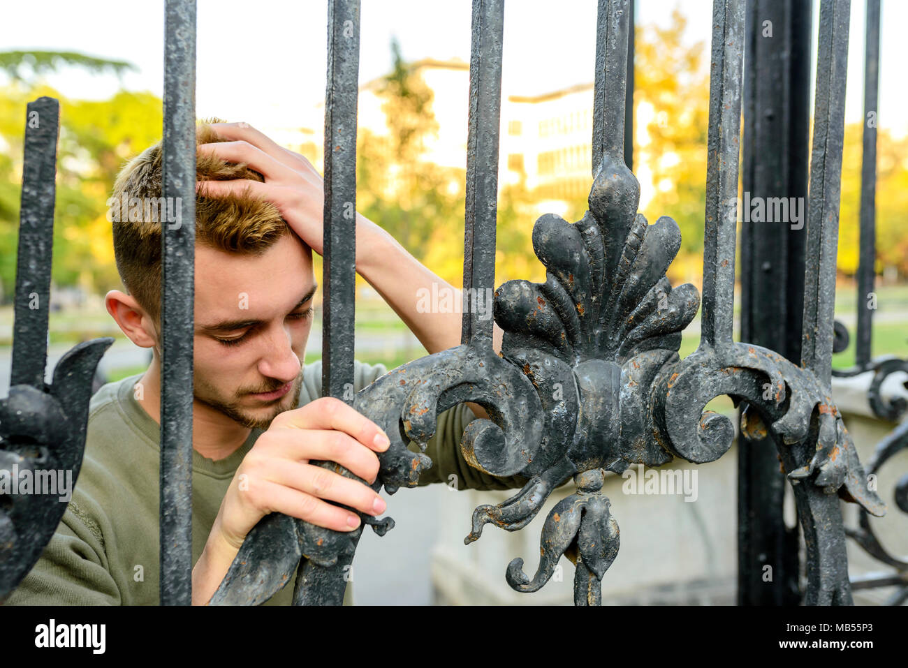 Giovane uomo bello con problemi vicino al cancello Foto Stock