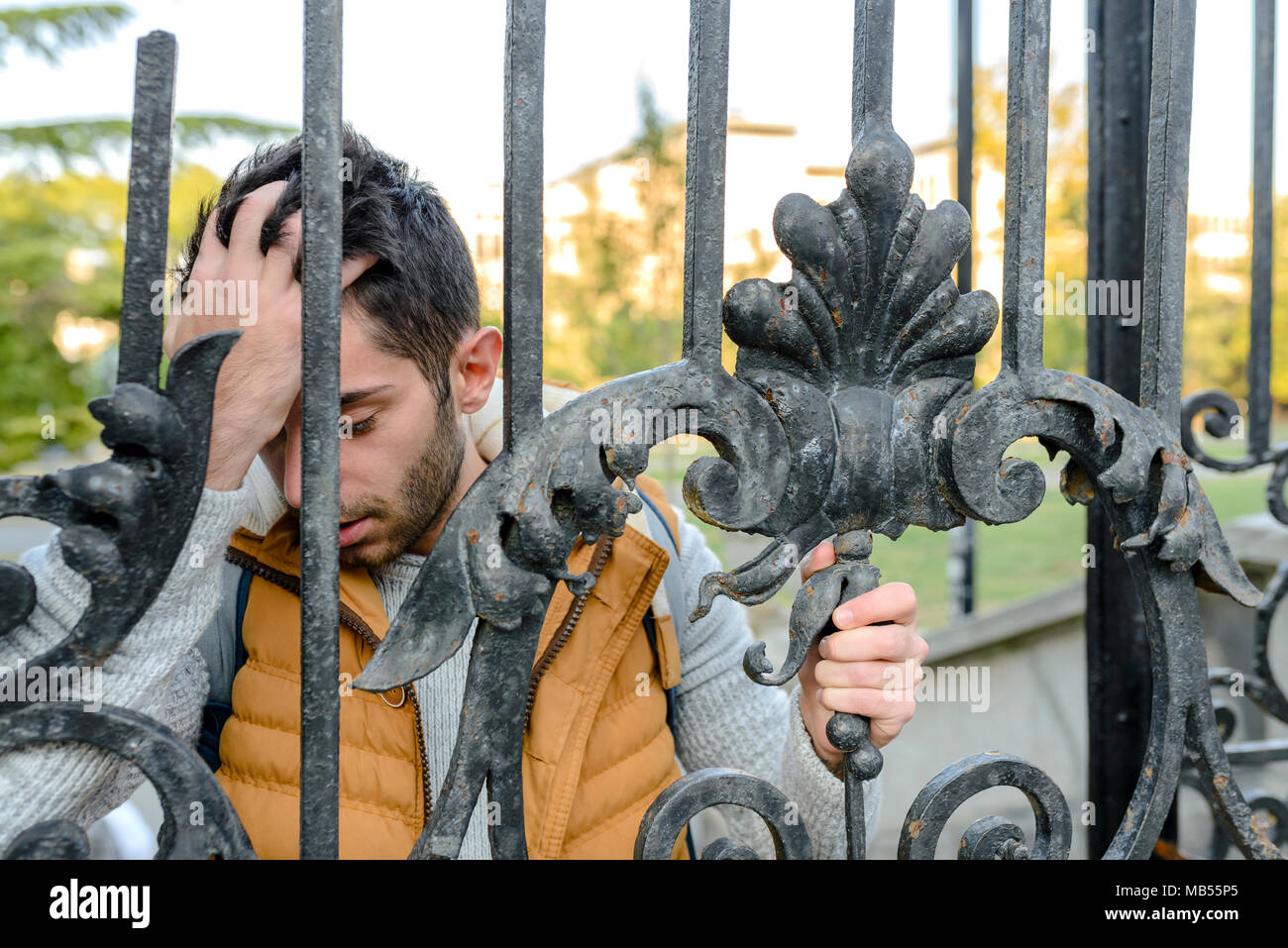 Giovane uomo bello con problemi vicino al cancello Foto Stock