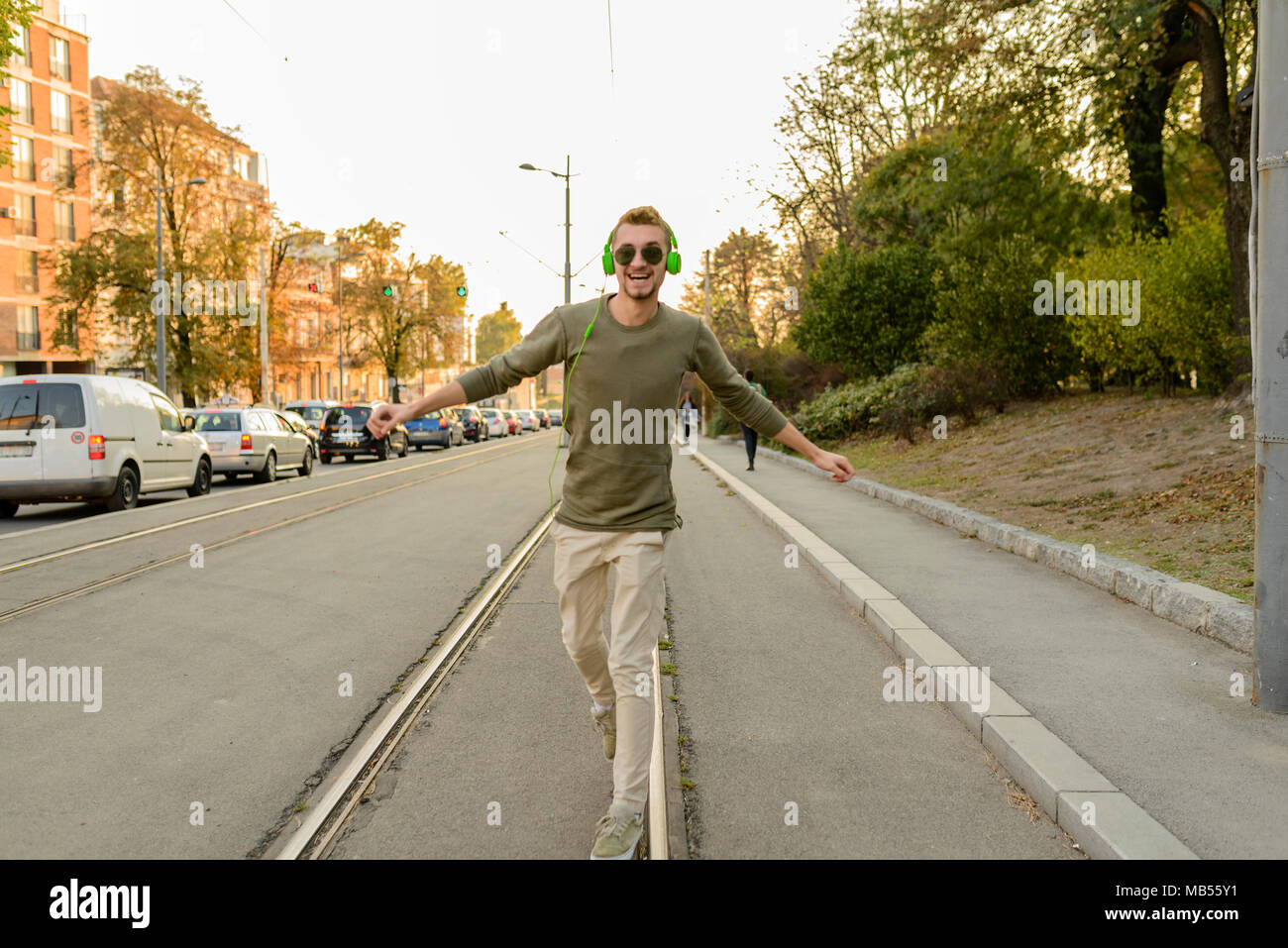 Giovane bello hipster è percorribile a piedi e il bilanciamento sui binari tranviari nella città Foto Stock