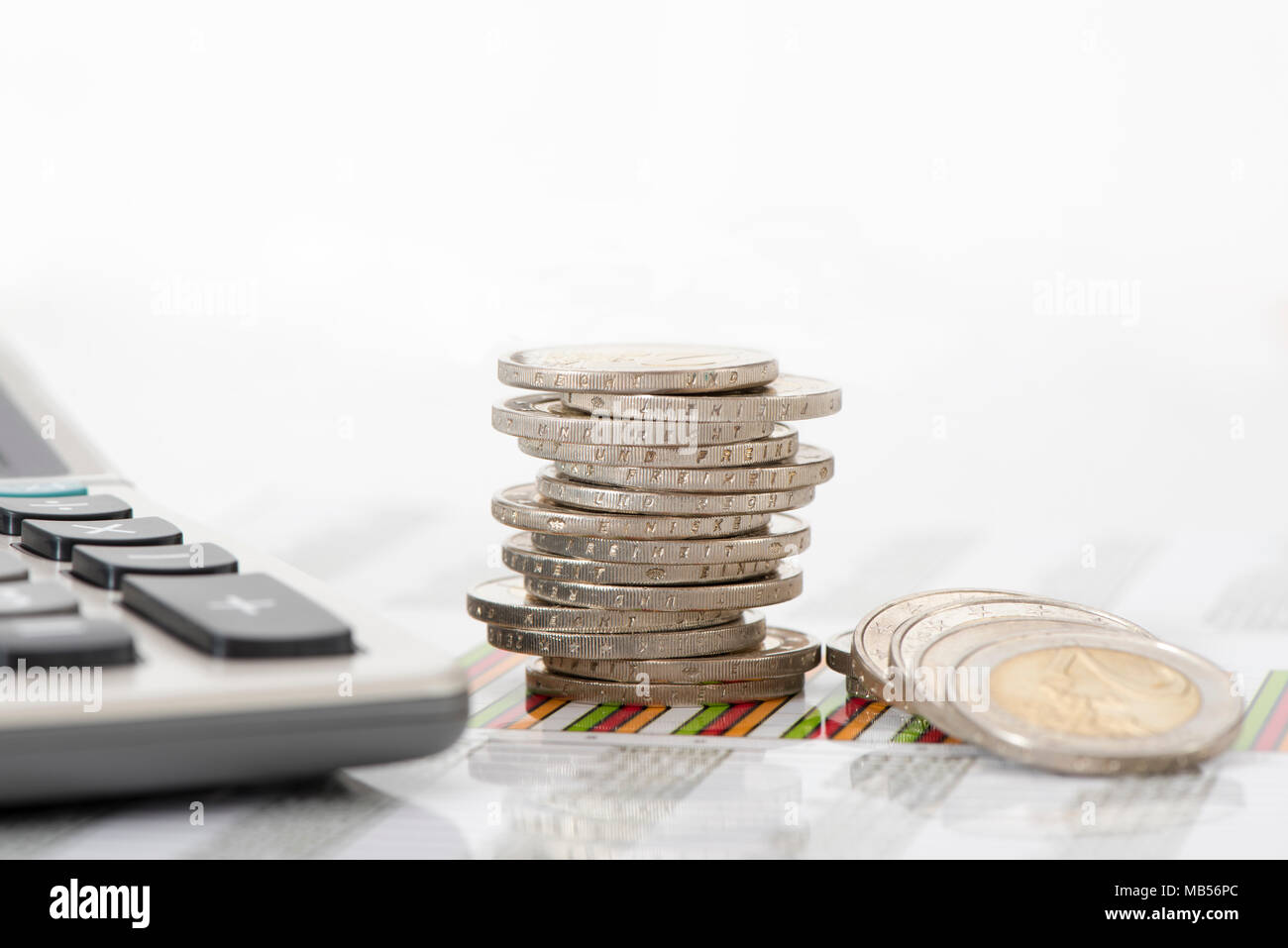 Impilate le monete in euro e la calcolatrice posa su attività finanziarie grafico Foto Stock