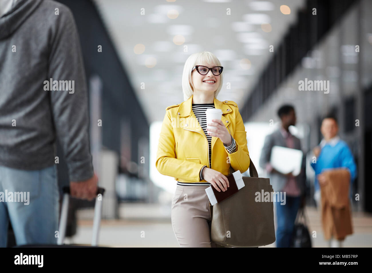 Giovani viaggiatori femmina con i bagagli, bere e documenti a piedi al contatore di registrazione per il check-in Foto Stock