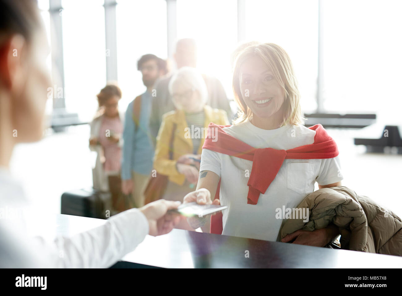 Felice traveler tenendo indietro i suoi documenti dopo il check-in al banco di registrazione in aeroporto prima della partenza Foto Stock