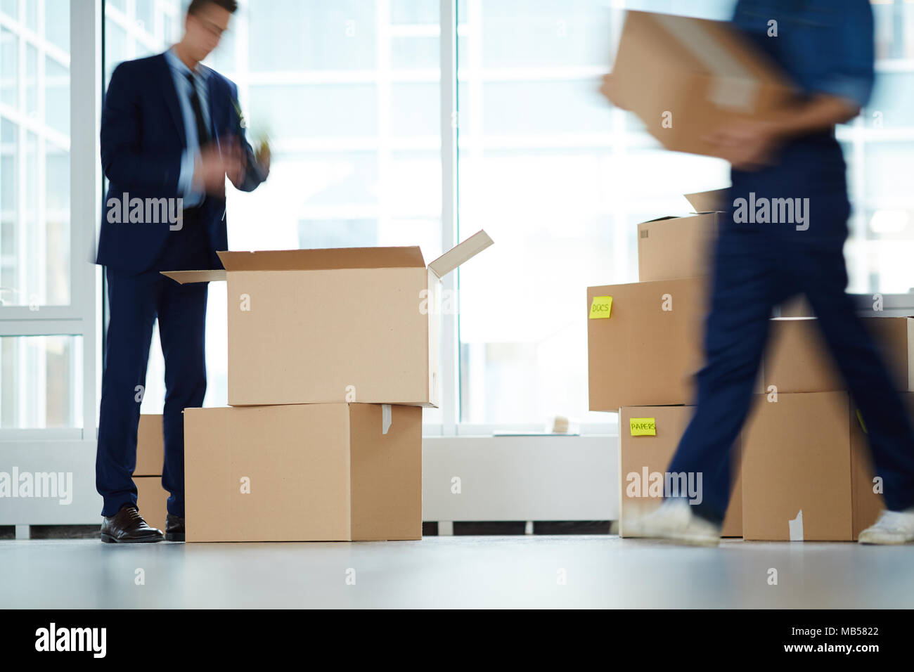 Imprenditore in piedi di fronte a scatola aperta dalla finestra di office center mentre il servizio di trasferimento lavoratore il trasporto dei colli Foto Stock