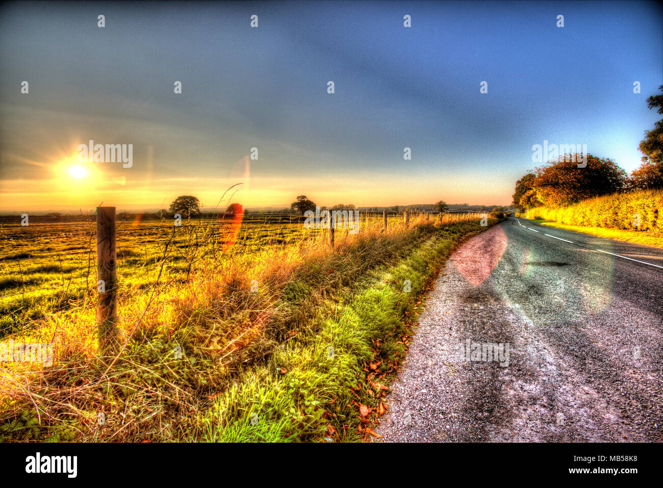 Villaggio di Shocklach, Cheshire, Inghilterra. Tramonto artistico la vista su una strada rurale e campo di Cheshire, nei pressi del villaggio di Shocklach. Foto Stock