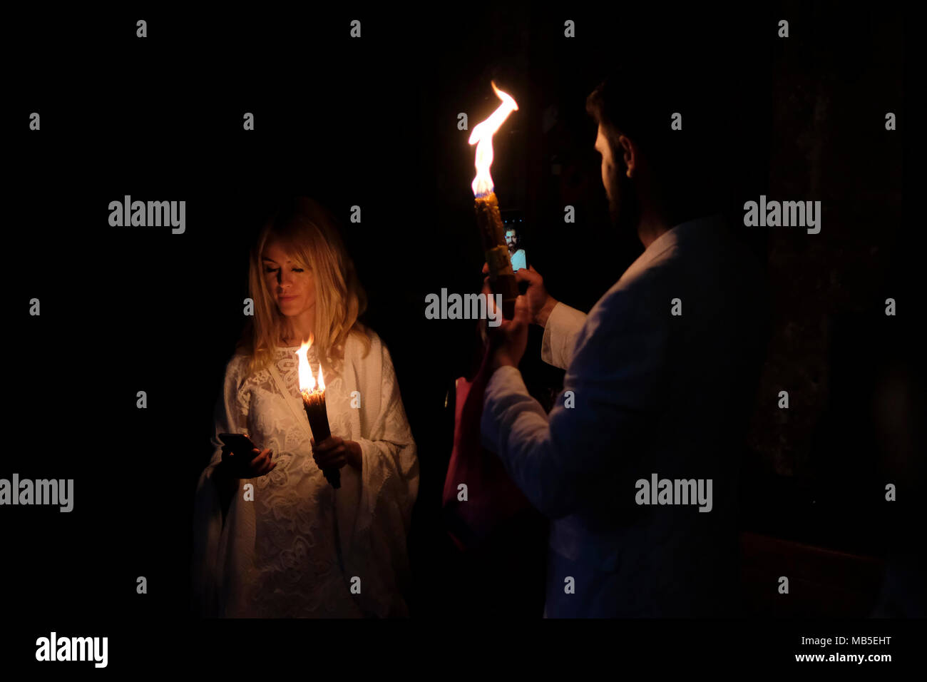 I cristiani ortodossi adoratori tenendo selfie con candele accese dal fuoco santo durante il Sabato Santo dentro la Chiesa del Santo Sepolcro nella città vecchia di Gerusalemme in Israele. Il fuoco santo è descritto da cristiani ortodossi come un miracolo che si verifica ogni anno presso la chiesa del Santo Sepolcro il sabato il giorno che precede la Pasqua ortodossa. Foto Stock