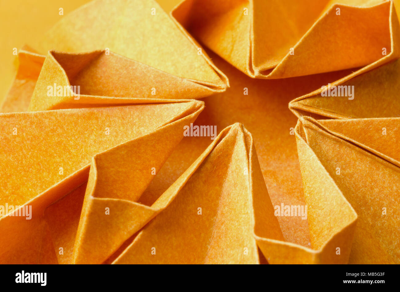 Macro della parte radiale di una trama carta arancione origami flower Foto Stock