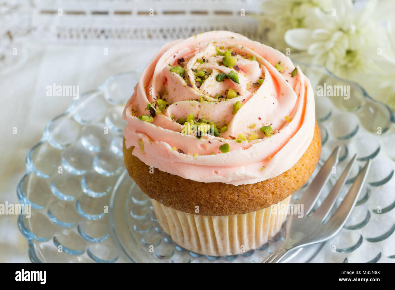 Rose smerigliati Cup cake con pistacchio irrora vicino sul vetro della piastra torta Foto Stock