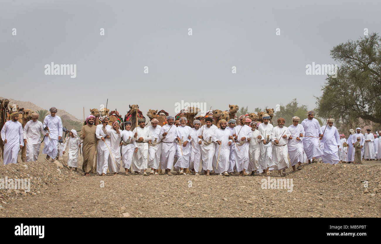 Ibri, Oman, 7 Aprile 2018: omani gli uomini camminare e ballare a seguito di una tradizionale gara di cammello Foto Stock