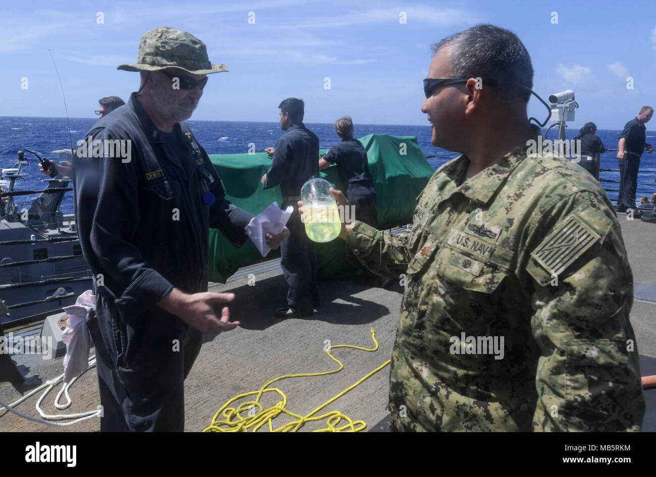 Chief Warrant Officer Jim Dewitt, assegnato all'Arleigh Burke-class guidato-missile destroyer USS O'Kane (DDG 77), descrive la purezza di marine il gasolio in O'Kane's serbatoi di servizio di Lt. La Cmdr. Paolo Duenas, assegnato a Costiera gruppo fluviale (CRG) 1, det. Guam, durante un test di esercizio in mare le capacità di rifornimento tra il contrassegno VI patrol craft e O'Kane, Feb 21, 2018. CRG-1, det. Guam, è in grado di condurre le operazioni di sicurezza marittima nell intero spettro del Naval, giunto e operazioni combinate. Inoltre, esso fornisce funzionalità aggiuntive di sicurezza del porto, avviato la sicurezza, un Foto Stock