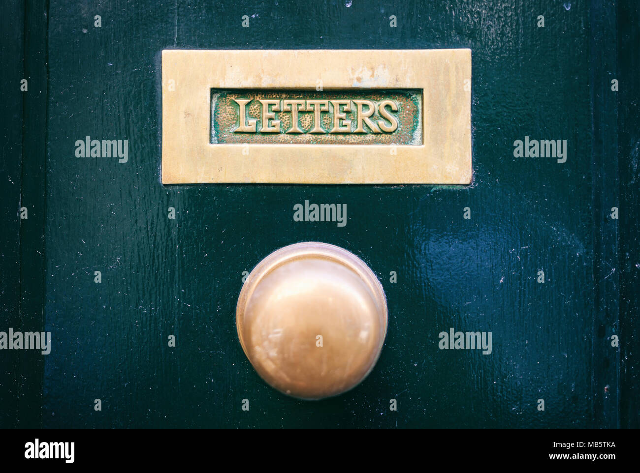 Ottone antico mail letter box e porta la manopola su un verde porta anteriore, lettere di testo Foto Stock