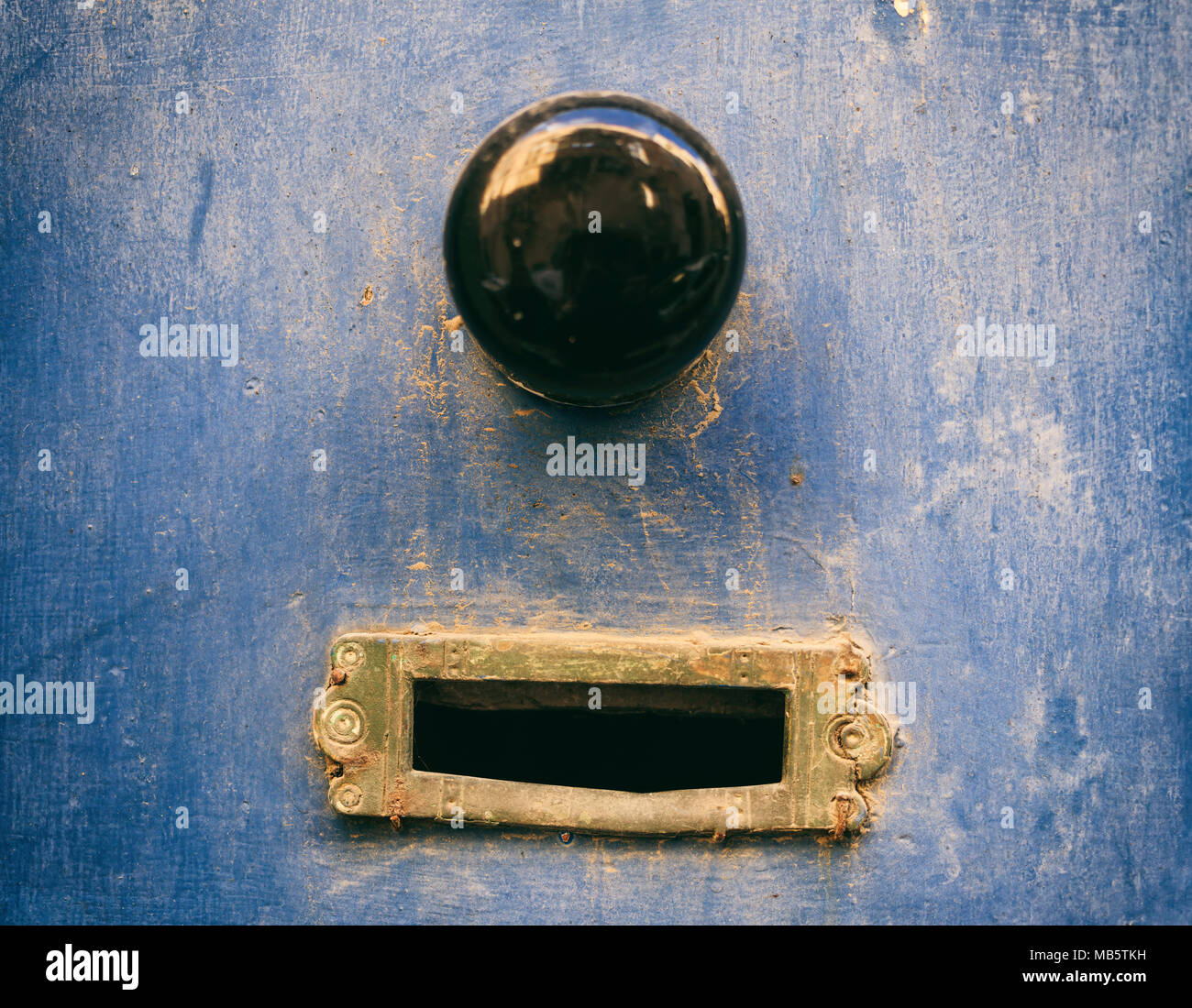 Ottone antico mail letter box e Porta Nera manopola su un alterato blu della porta anteriore Foto Stock