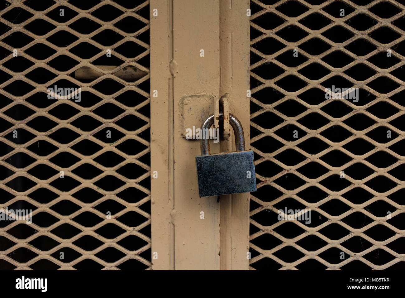 Porta bloccata. Il lucchetto chiuso su un vecchio metallo giallo porta, primo piano Foto Stock