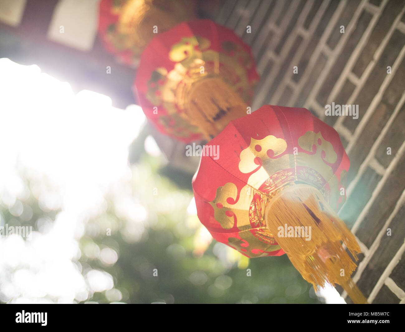 Cinese lanterne di carta con spurgo di luce su un grigio arco in mattoni con legno intarsiato in Seychelles Foto Stock