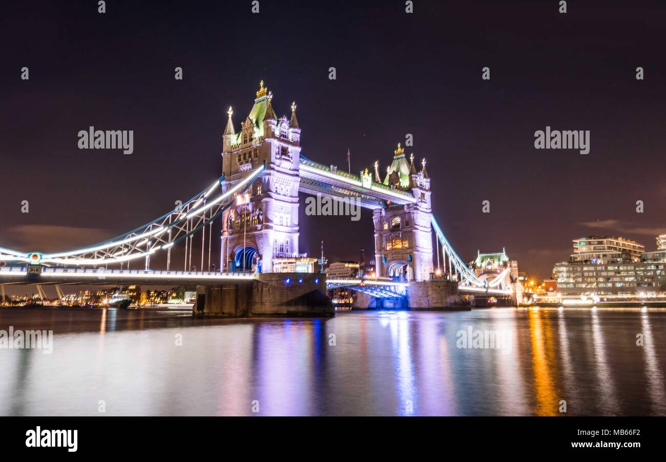 La riflessione del Tower Bridge di Londra di notte Foto Stock