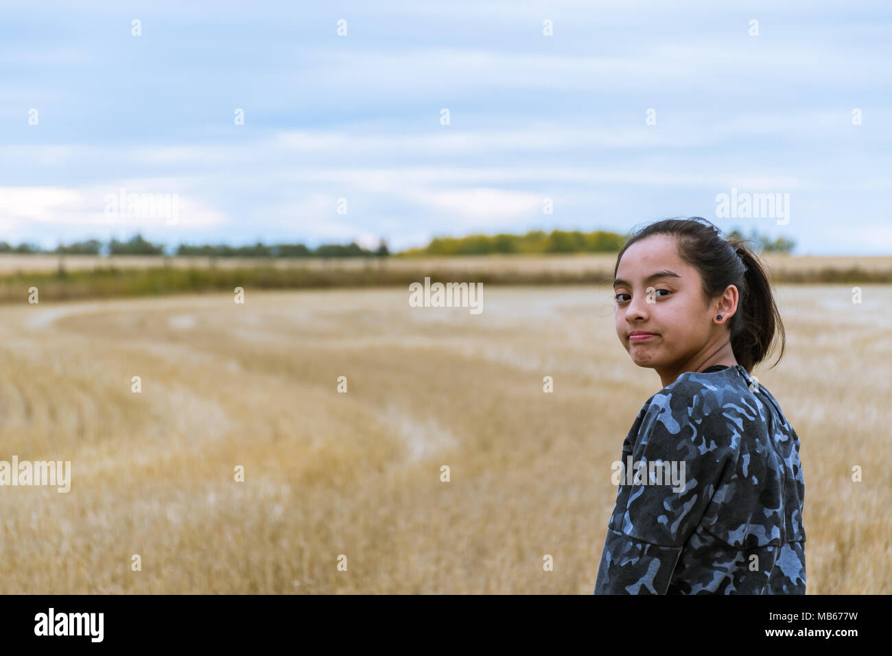 Ragazza giovane esplorando in un campo dopo un raccolto Foto Stock