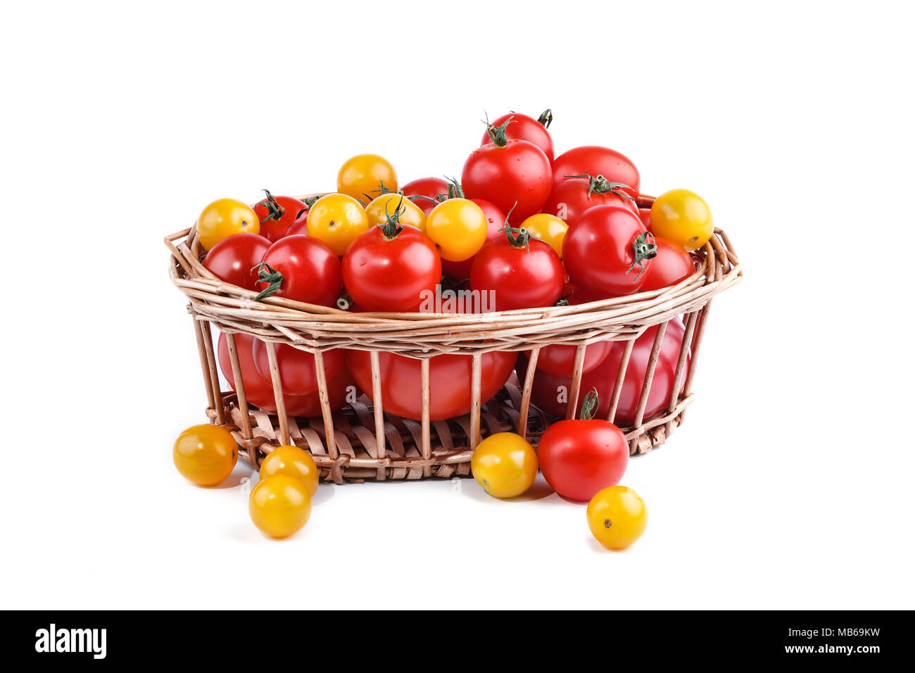 Il giallo e il rosso dei pomodori giacciono nel cesto su uno sfondo bianco. Foto Stock