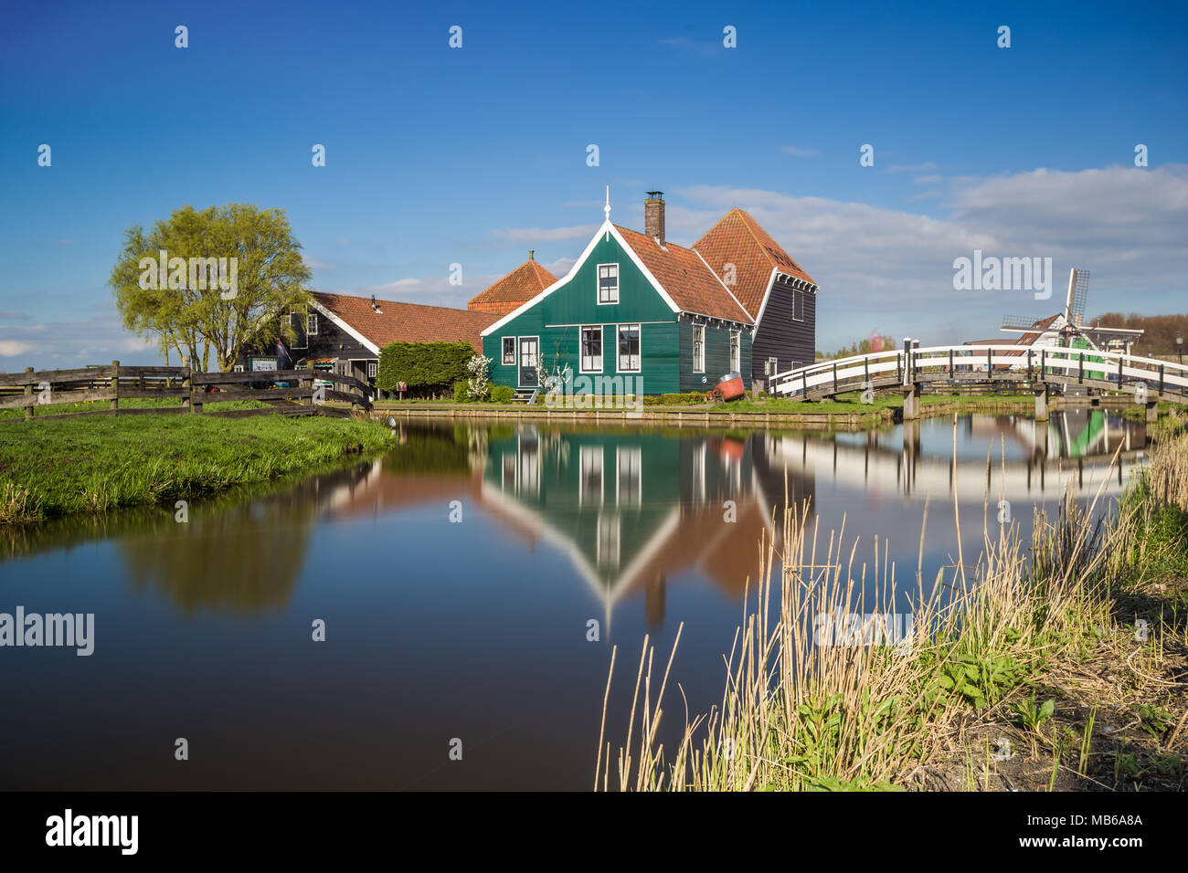 Case in legno è riflessa nelle acque blu del fiume Zaan Zaanse Schans Olanda settentrionale dei Paesi Bassi in Europa Foto Stock
