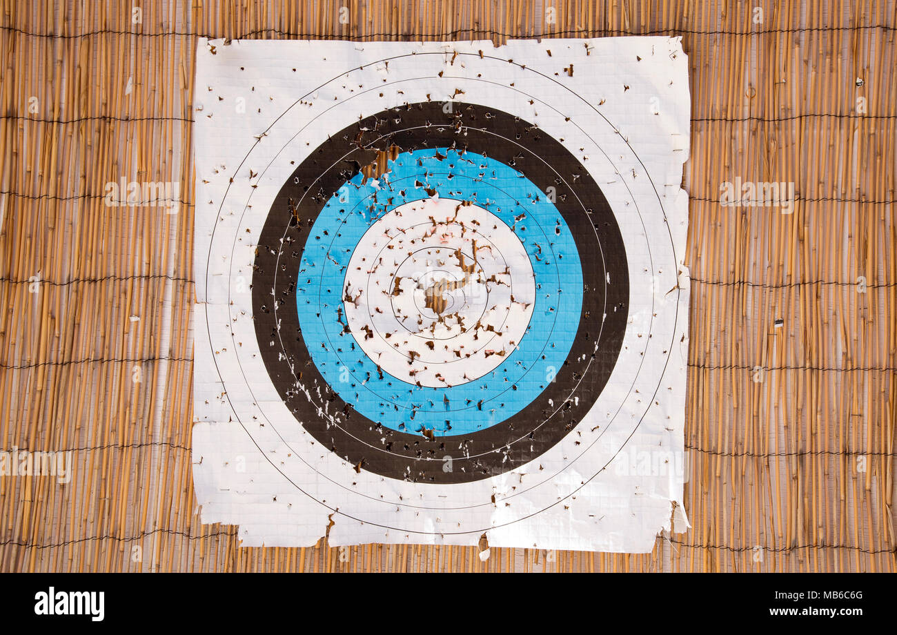Una carta bersaglio tiro con l'arco faccia con molti fori strappata nell'area bersaglio Foto Stock