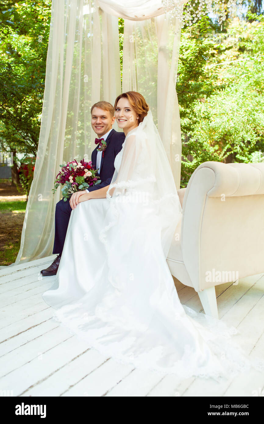 Happy sposi tenendo le mani e seduto sul divano beige in posizione di parcheggio Foto Stock