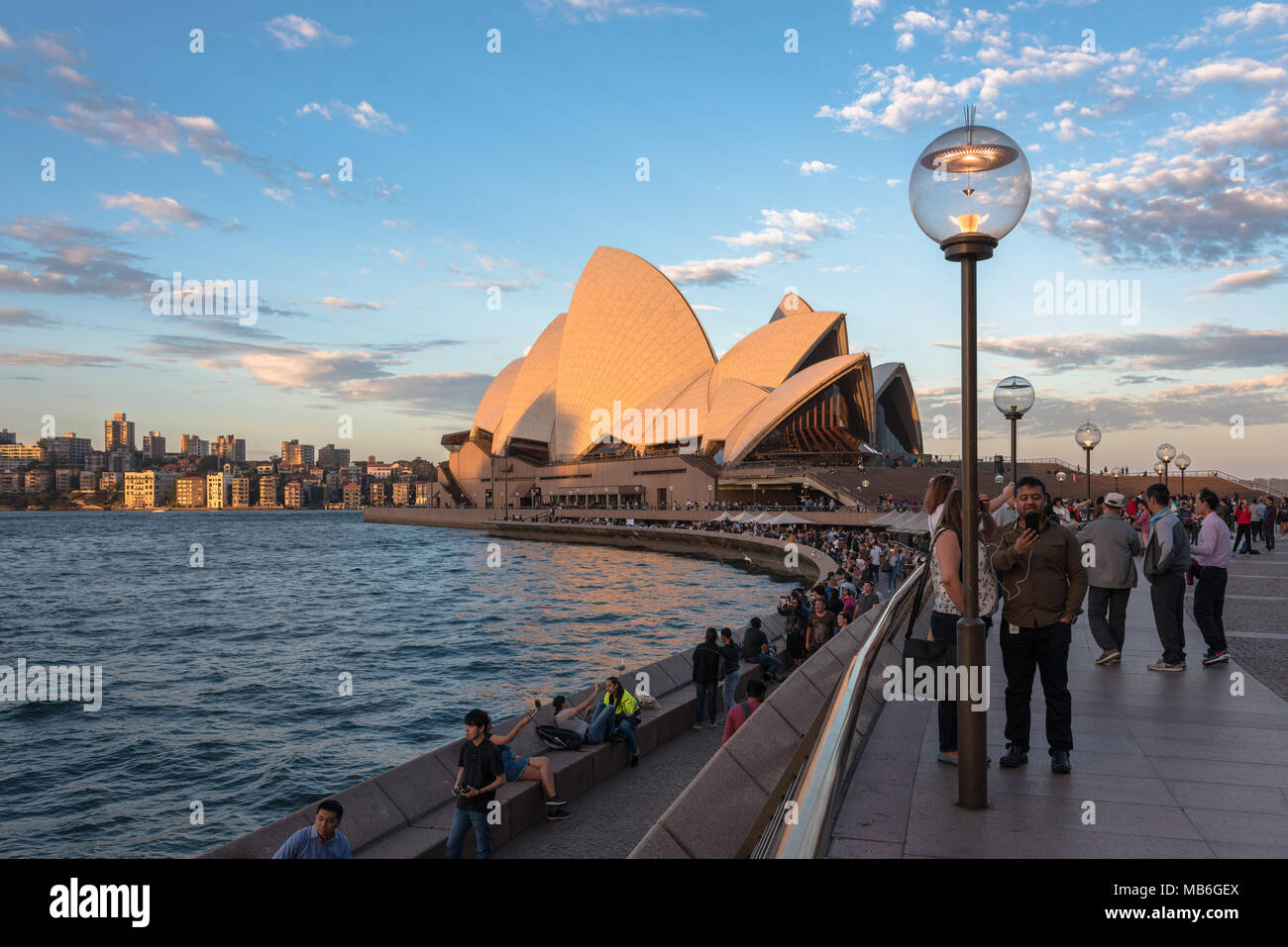 I turisti at Bennelong Point con la Sydney Opera House a ora d'oro Foto Stock