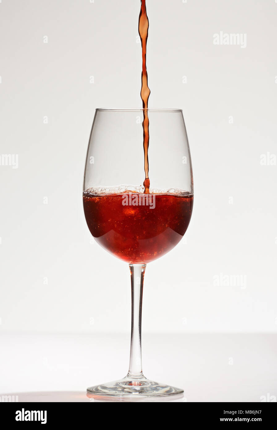 Close-up di versare il vino rosso in vetro isolato su sfondo bianco Foto Stock