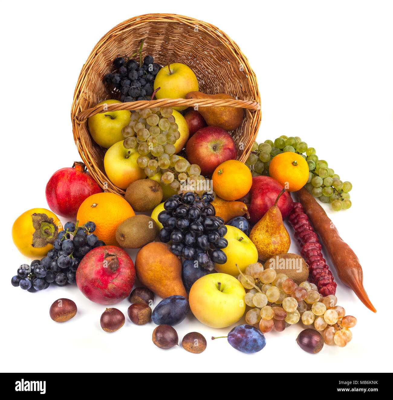 Mele e altri frutti in un cesto di vimini su uno sfondo bianco. Foto Stock