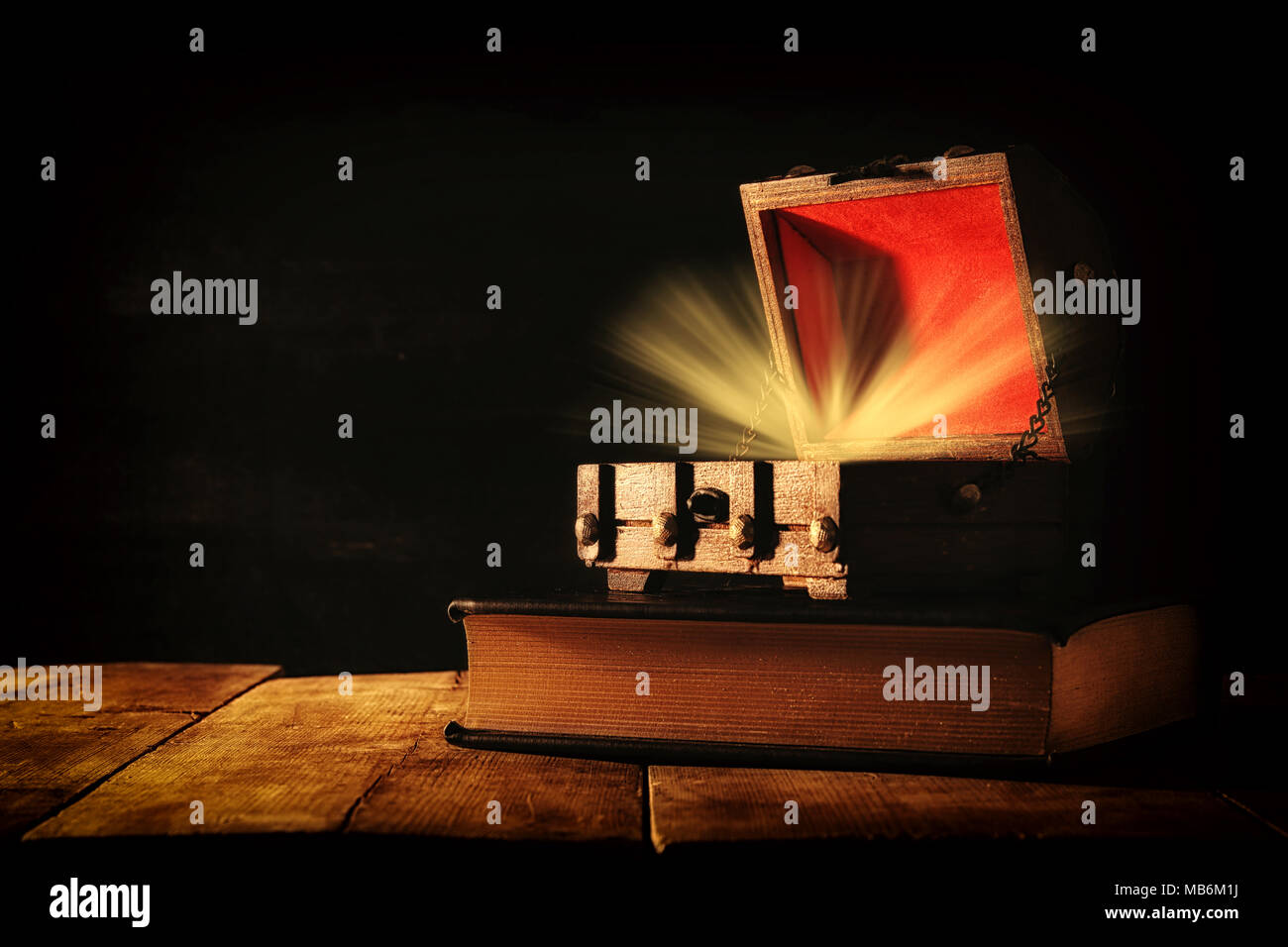 Immagine del misterioso tesoro con luce su un vecchio libro sul tavolo di legno Foto Stock