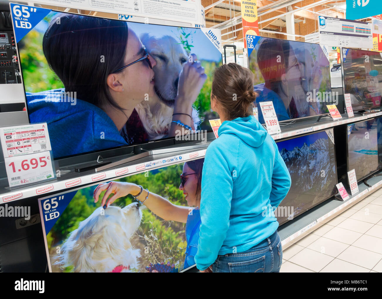 Donna che guarda al nuovo Samsung High definition 4k curva schermi TV in negozio elettrico Foto Stock