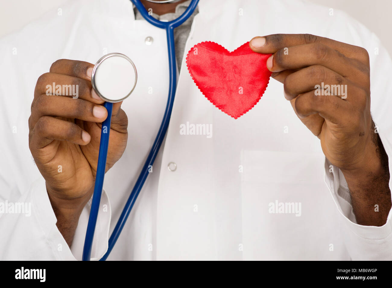 Close up uomo medicina mani e mostrando in mani un cuore rosso in giocattolo e stetoscopio. Foto Stock