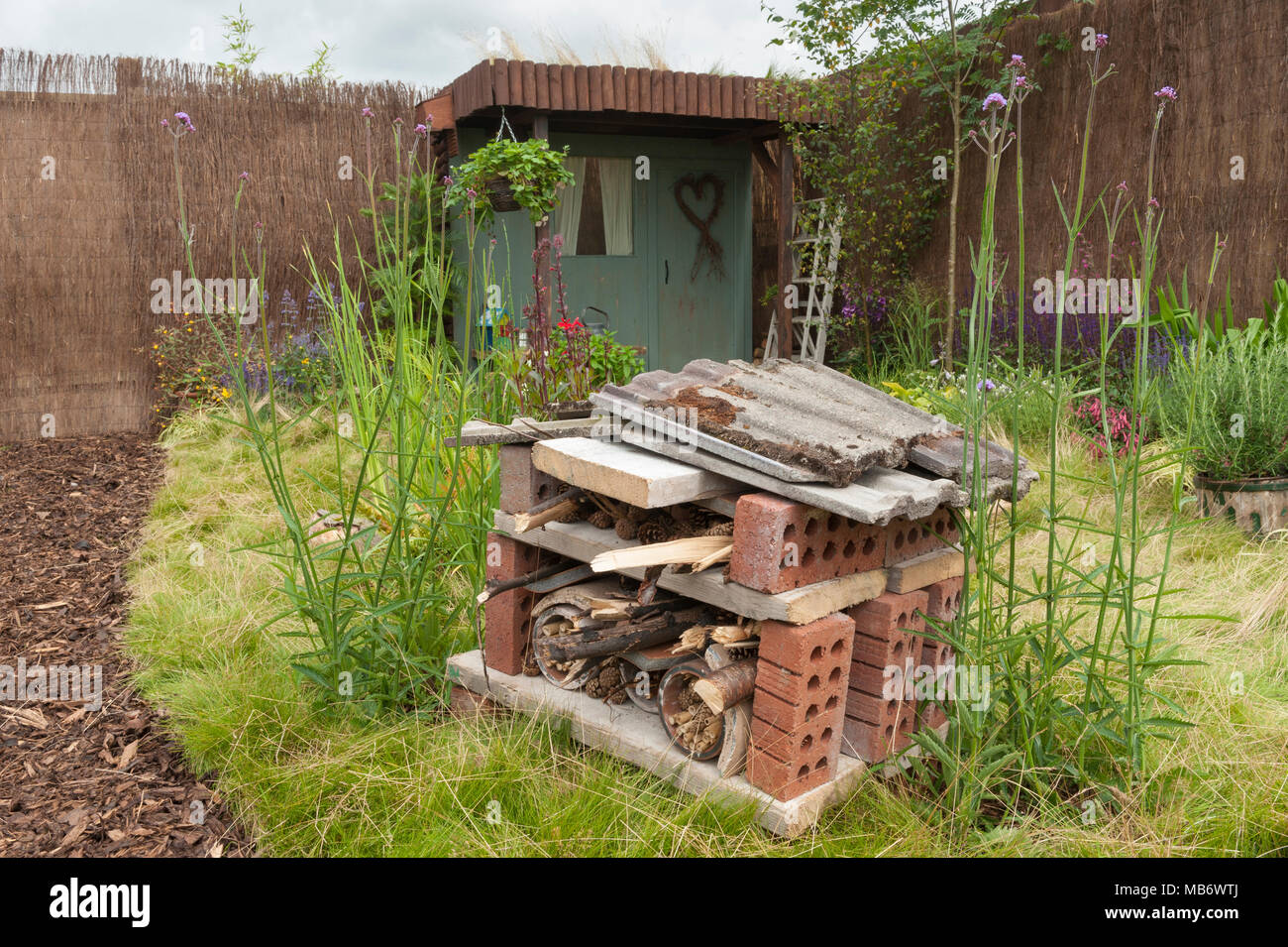 Bug hotel fornendo habitat naturale per la fauna selvatica, fiori selvatici e tettoia in legno - "Home Sweet Home" mostra il giardino - RHS Flower Show, Tatton Park, Inghilterra, Regno Unito. Foto Stock