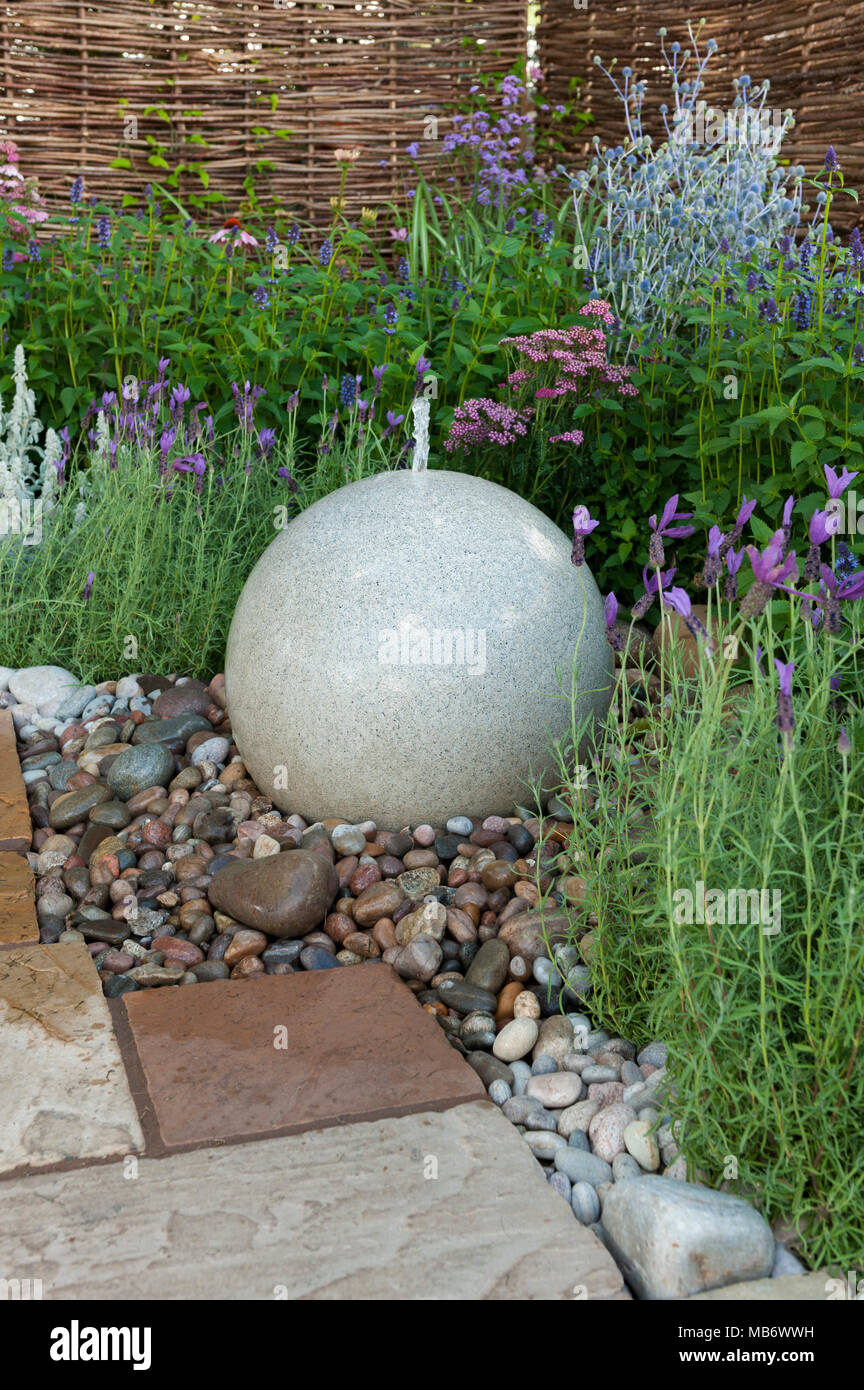 Pietra sferica funzione acqua sul confine delle colorate fiori - 'Drisme solo sogni' mostrano giardino, RHS Flower Show, Tatton Park, Inghilterra, Regno Unito. Foto Stock