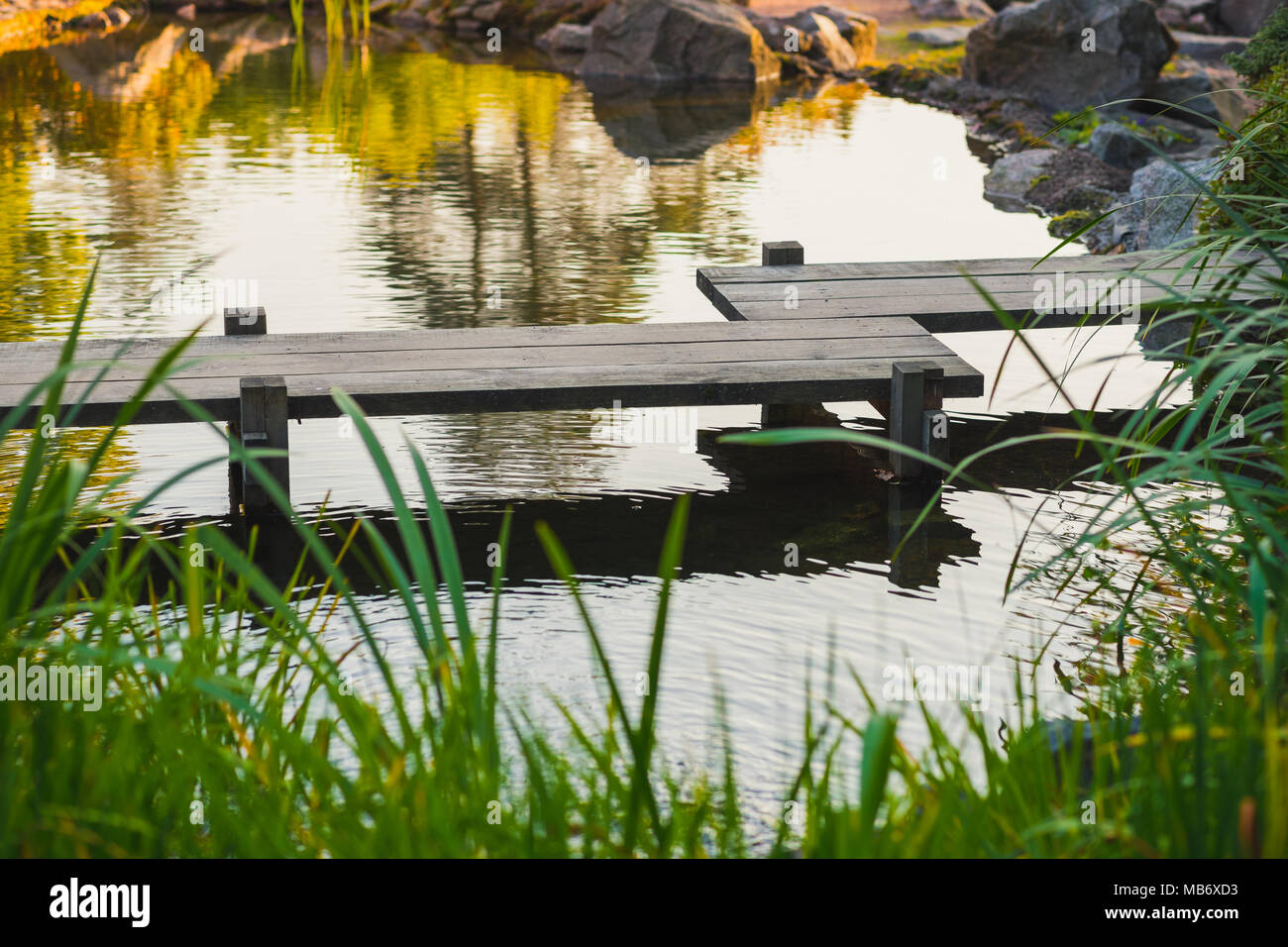 Ponte di legno in stile giapponese su un laghetto in giardino Foto Stock