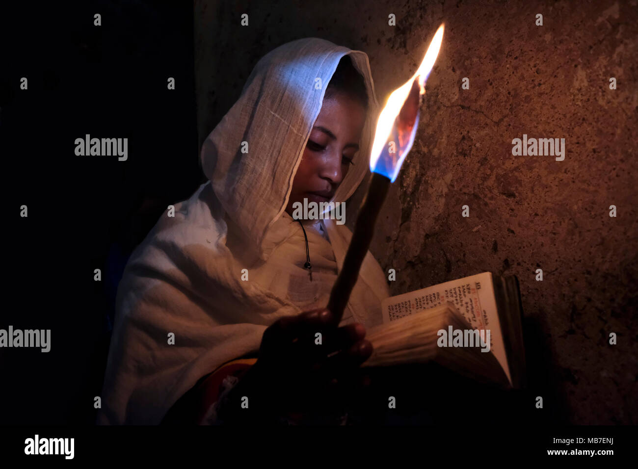 Un pellegrino cristiano ortodosso etiope tiene una candela mentre prega durante la cerimonia del Santo fuoco al monastero di Deir El-Sultan situato sul tetto della Chiesa del Santo Sepolcro nella città vecchia di Gerusalemme Est Israele. I cristiani etiopi commemorano gli eventi intorno alla crocifissione di Gesù Cristo, che porta alla sua risurrezione di Pasqua, che nella lingua amharica, viene chiamata Fasika, originata dalla parola greca Pascha. Foto Stock
