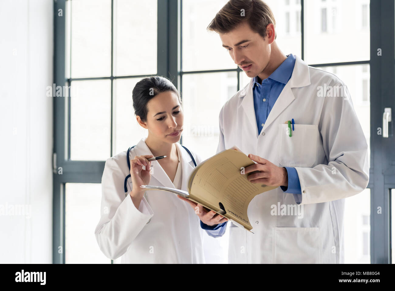 Due medici verificare insieme il record di medica di un paziente Foto Stock