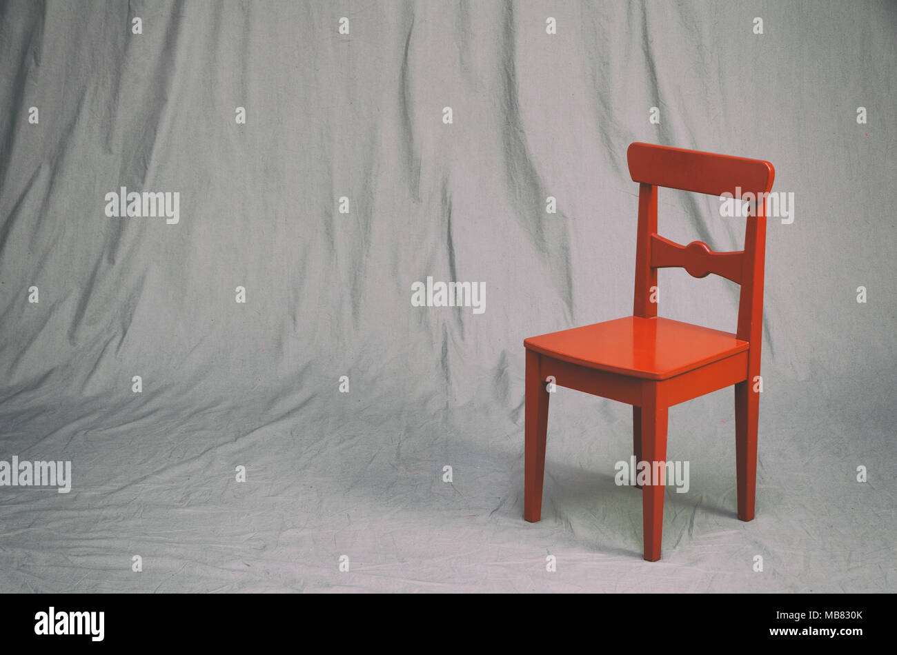 Piccola sedia rossa su un grungy grigio di sfondo per studio. vintage effetti di filtro. Foto Stock