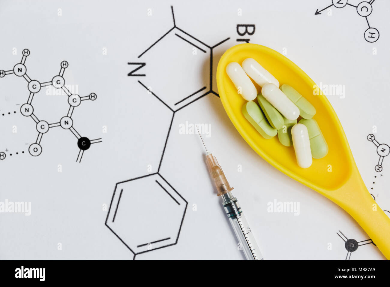 Assortimento di pillole, compresse e capsule in giallo cucchiaio, siringa su sfondo bianco con formula chimica. Foto Stock