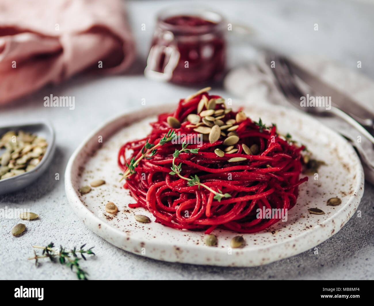 Barbabietole tostate e timo spaghetti con i semi di zucca in craft piastra sul cemento grigio Sfondo. Idee e ricette per una sana vegetariano vegano la cena. Messa a fuoco selettiva. Foto Stock