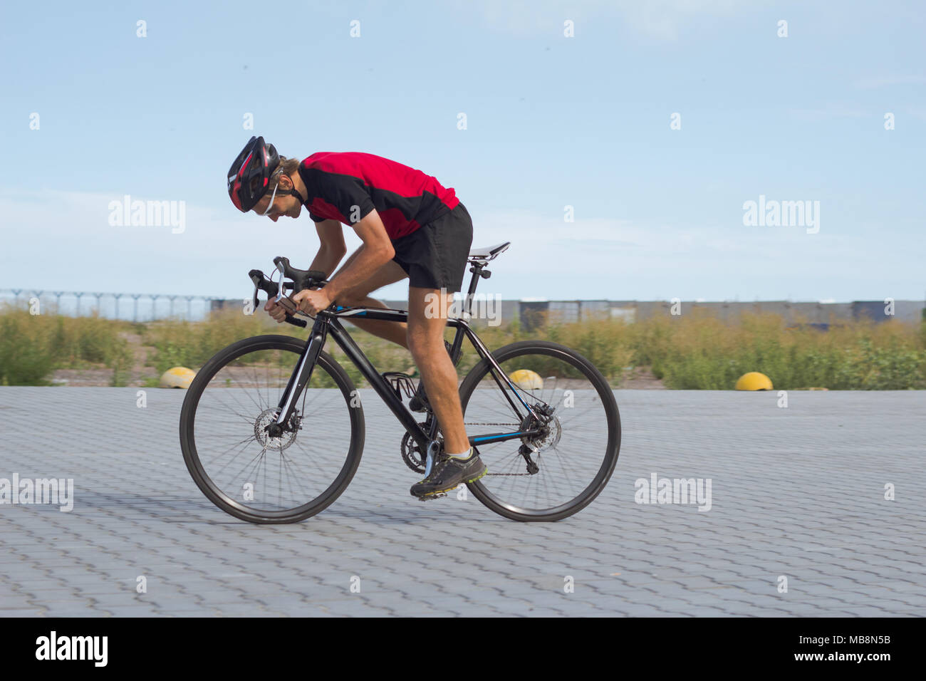 Professional ciclista in casco e abbigliamento sportivo corsi di formazione su strada vuota Foto Stock