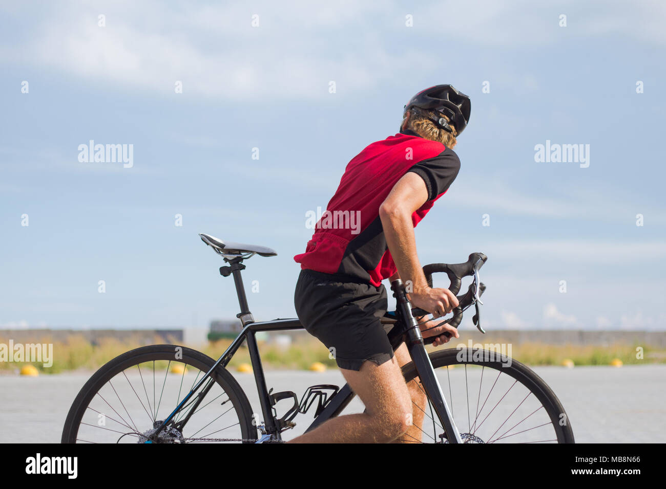 Professional ciclista in casco e abbigliamento sportivo corsi di formazione su strada vuota Foto Stock