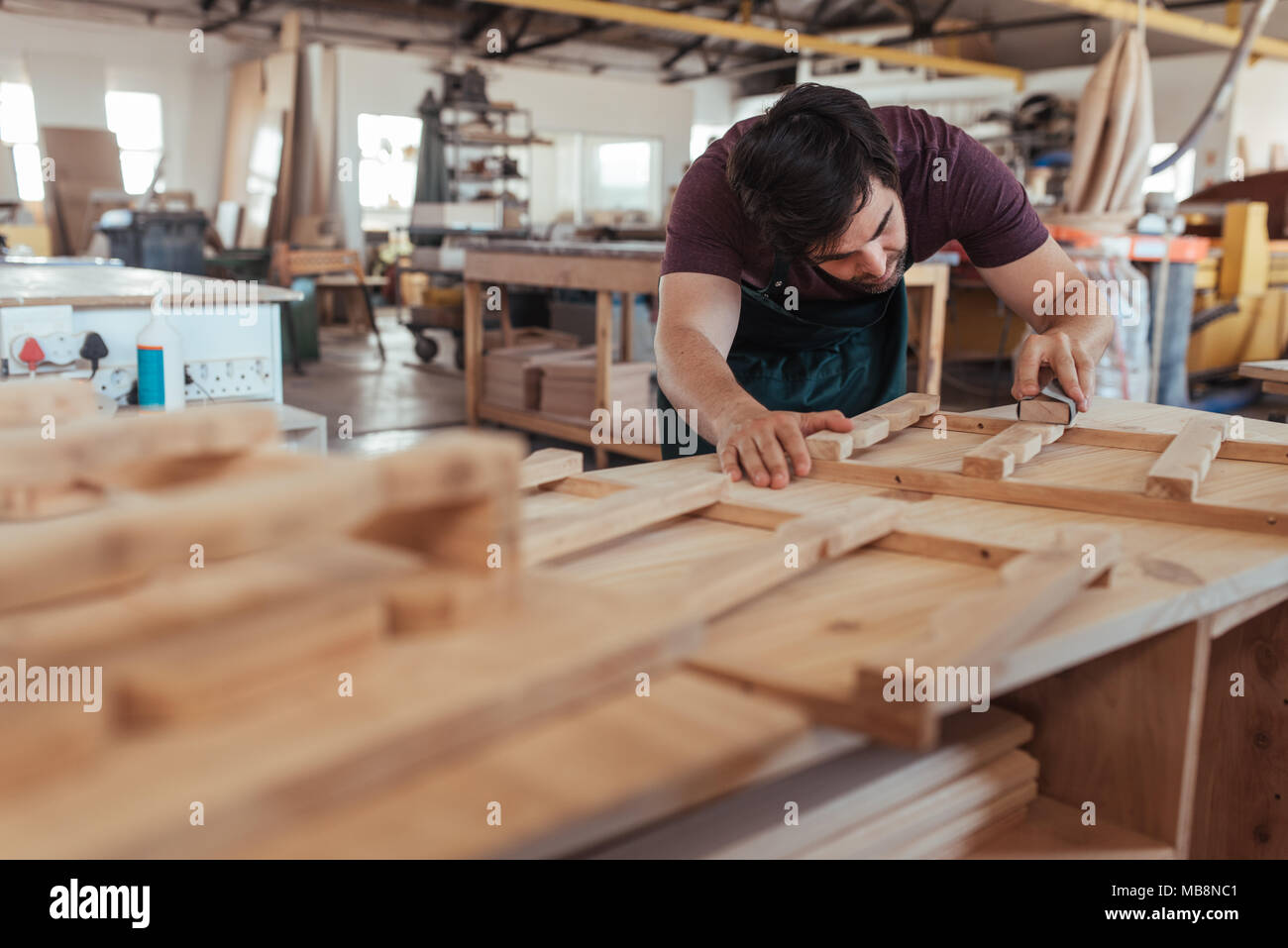 Artigiano la levigazione manuale dei pezzi di legno nel suo laboratorio Foto Stock