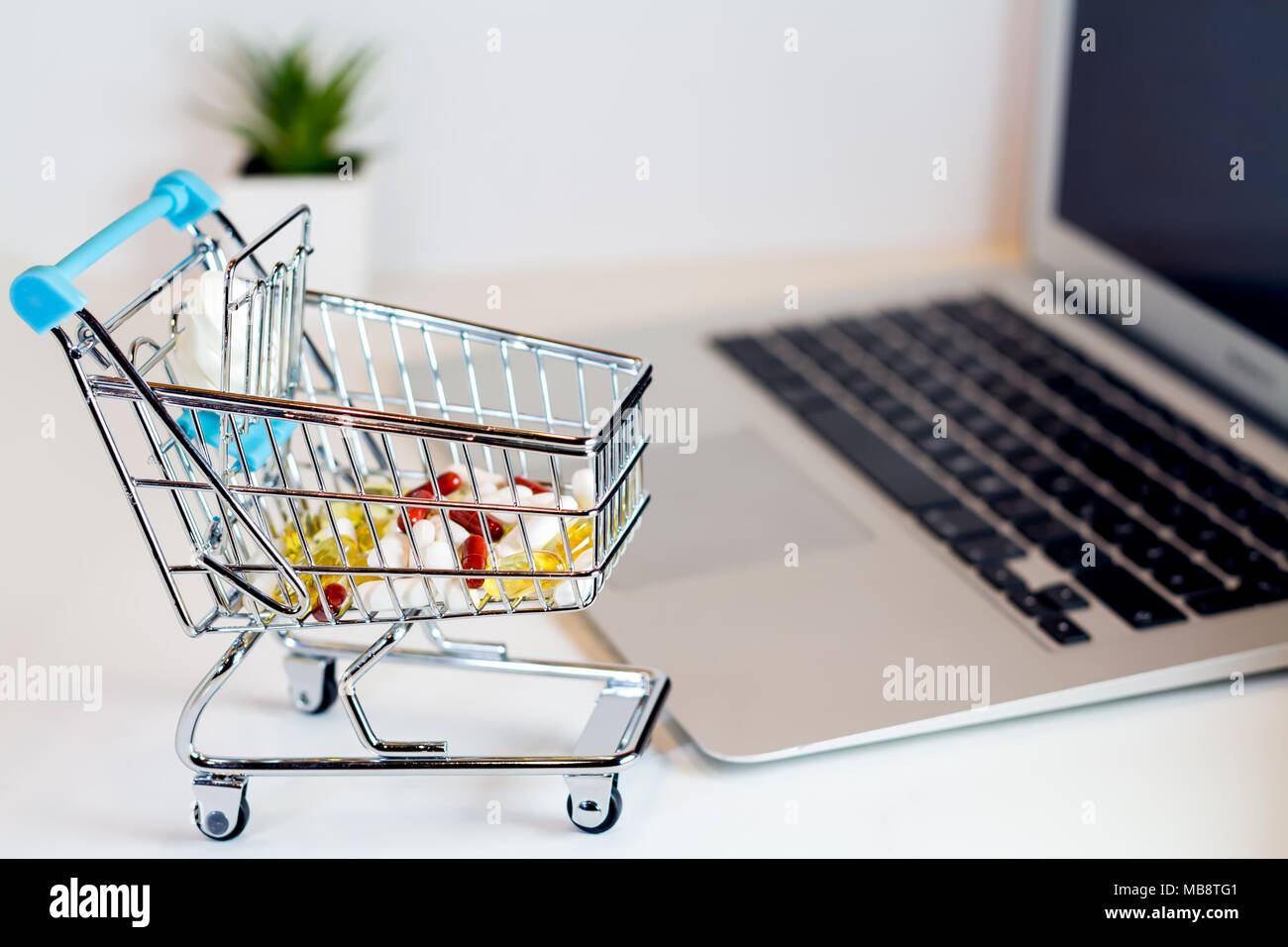 Supplementi online shopping farmaceutica concetto, shopping cart collocato su laptop isolato Foto Stock