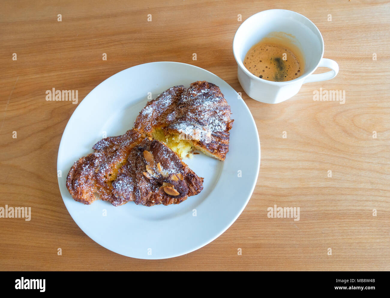 Un croissant alle mandorle e caffè espresso, una rinomata prima colazione continentale Foto Stock
