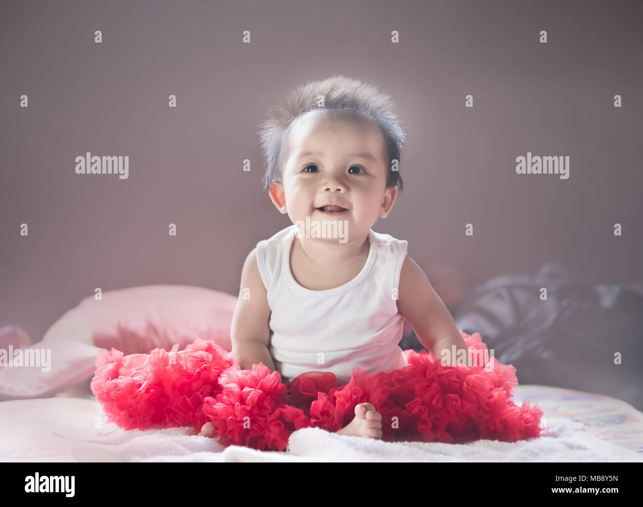 Asian new born baby sit e sorriso su un letto in camera da letto. Foto Stock