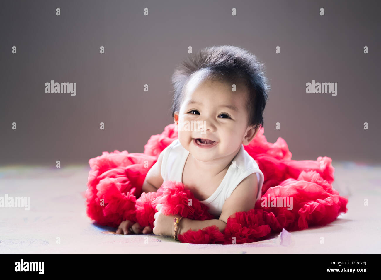 Asian new born baby sit e sorriso su un letto in camera da letto. Foto Stock